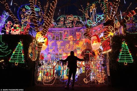 a person standing in front of a house covered in christmas lights