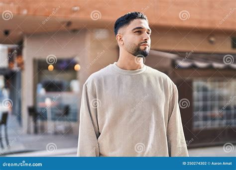 Young Arab Man With Relaxed Expression Standing At Street Stock Photo