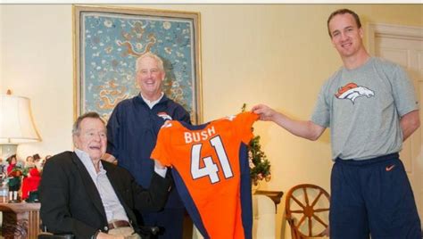 Two Men Are Holding Up A Jersey While Another Man Is Sitting In A Wheel Chair