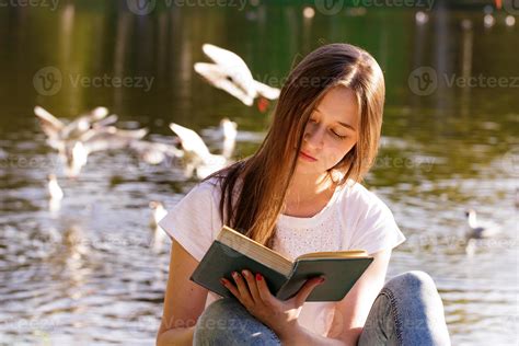 A Young Woman Sitting By The Lake Reading A Book 5884531 Stock Photo At