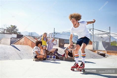 Friends watching man roller skating at sunny skate park — Men, on the ...