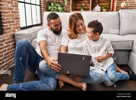 Familia viendo una película abrazándose uno al otro sentado en el suelo