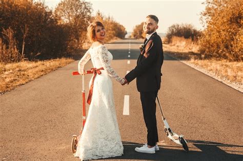 Pareja De Novios Sonriente Montando En Scooters A Lo Largo De La