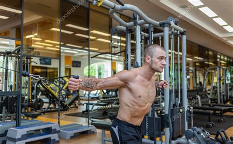 Muscular culturista con ejercicios de torso desnudo en la máquina de