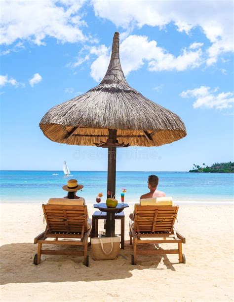 Man And Woman On A Tropical Beach With Chairs And Umbrella In Tropical