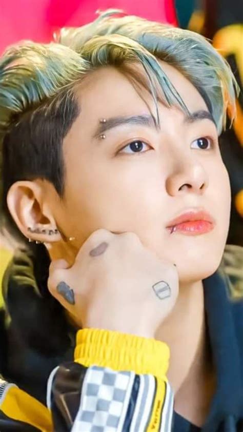 A Young Man With Green Hair And Piercings On His Ears Looking At The Camera