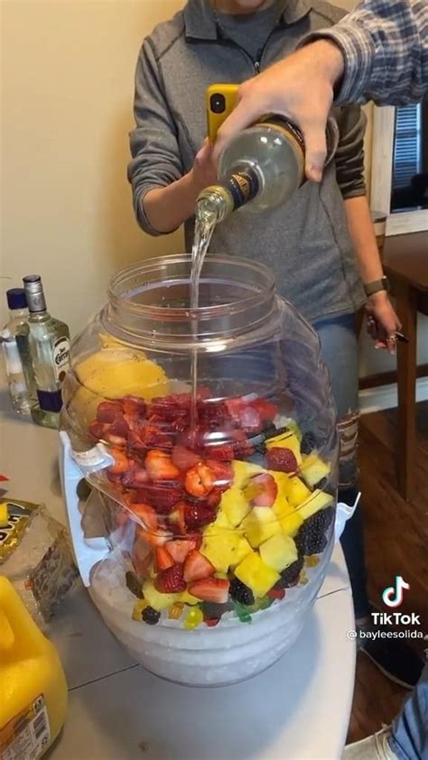 A Person Pouring Water Into A Bowl Filled With Fruit