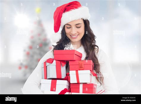 Composite Image Of Festive Brunette Holding Pile Of Gifts Stock Photo