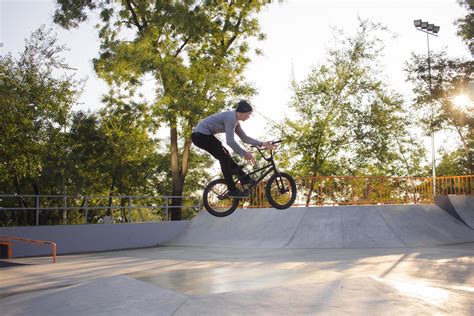 BMX rider training and do tricks in street plaza, bicyxle stunt rider in cocncrete skatepark ...