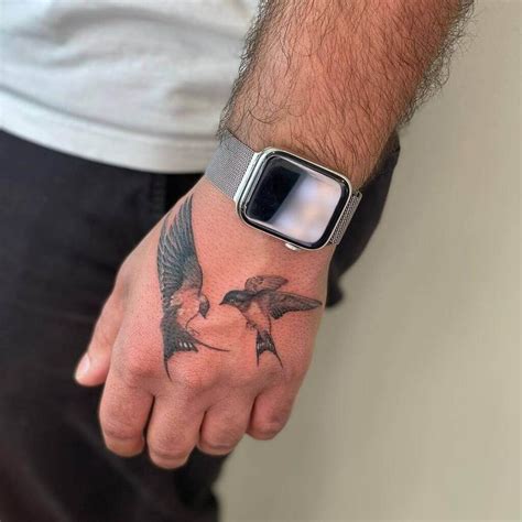 A Man S Arm With A Bird Tattoo On It And A Smart Phone In His Hand