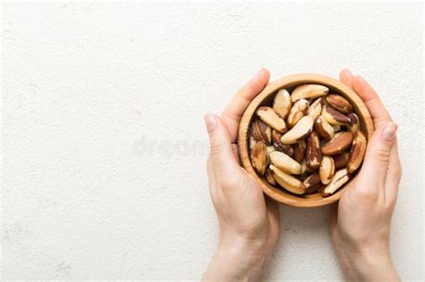 Woman Hands Holding A Wooden Bowl With Brazil Or Bertholletia Nuts