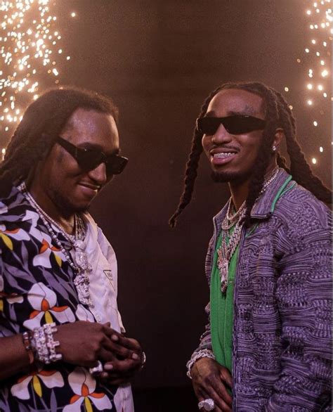 Two Men Standing Next To Each Other With Fireworks In The Background