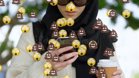 Animation Of Od Falling Emojis Over Woman In Hijab Using Smartphone