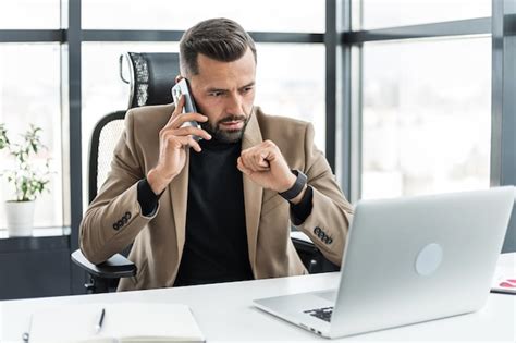 Un hombre de negocios serio está hablando por su teléfono celular y