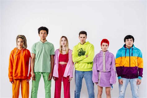 Stylish Men And Women In Colorful Clothes Looking At Camera Against