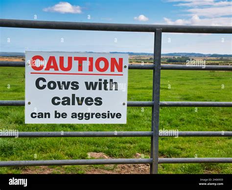 A Sign With Red And Black Lettering Fixed To A Gate To A Farm Field