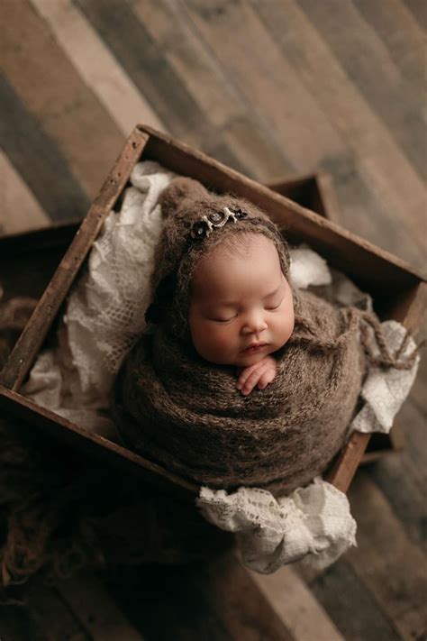 A Newborn Baby Is Curled Up In A Box