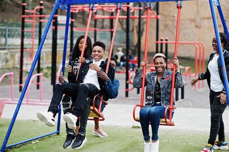 Young millennials african friends on playground, slide and swing. Happy ...