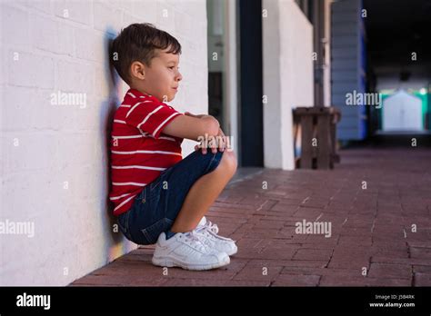 Enfant Accroupi Adossé Banque De Photographies Et Dimages à Haute