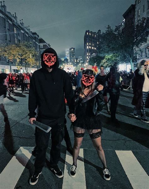 Two People Wearing Masks Walking Across A Crosswalk In The City At