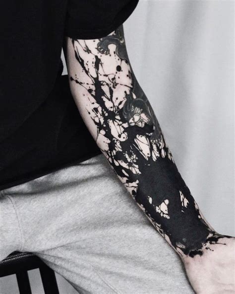 A Man S Arm Covered In Black Ink With White Paint Splattered On It