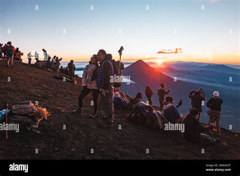 tourists pose for photos at sunrise atop the summit of Acatenango ...