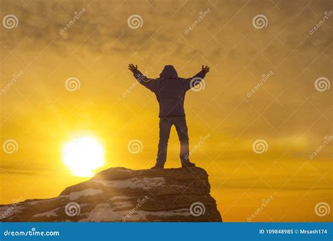 Man At The Top Of The Mountain Holding Up His Hand Against The