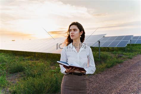 日落时分投资者女性站在地上的太阳能电池板附近看书高清摄影大图 千库网