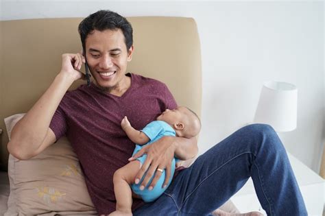 Feliz jovem pai asiático segurando seu doce adorável bebê recém nascido