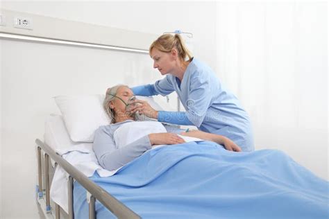 Nurse Puts Oxygen Mask On Elderly Woman Patient Lying In The Hospital