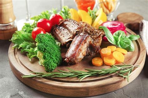 Premium Photo Delicious Roasted Ribs And Vegetables On Wooden Board