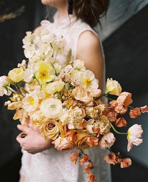 A Woman Holding A Bouquet Of Flowers In Her Hands