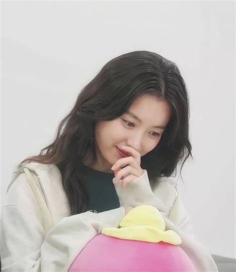 A Woman Sitting At A Table With A Pink And Yellow Object In Front Of Her