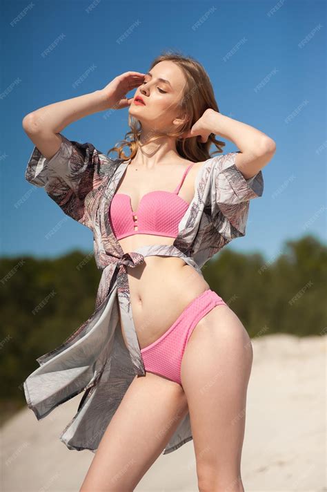 Premium Photo A Girl In A Pink Bikini Poses In Front Of A Blue Sky