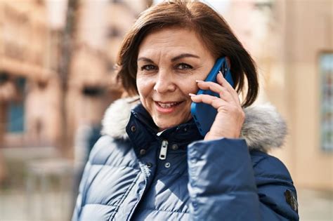 Mujer de mediana edad sonriendo confiada hablando por el teléfono