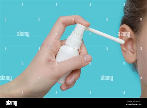 Mother Spraying Medication Into Daughters Ear On Light Blue Background