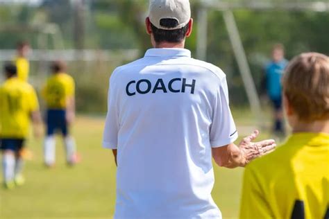 Back Of Football Coach Wearing White Coach Shirt At An Outdoor Sport