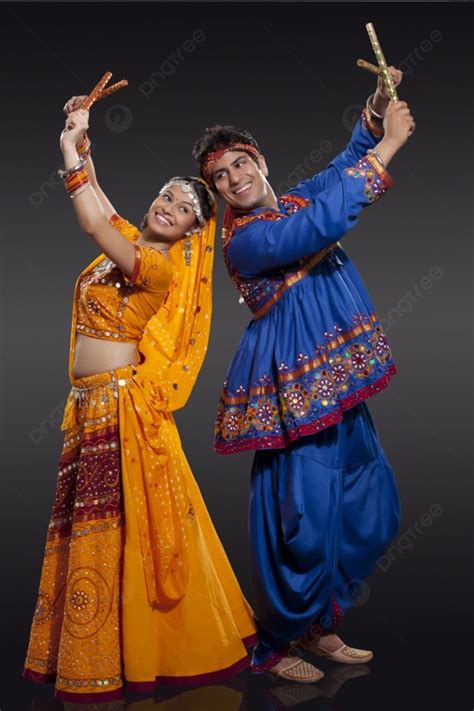 Happy Young Indian Couple Performing Dandiya Raas Over Black Background