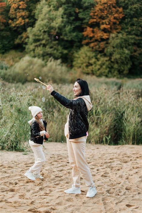 Mom And Daughter Have Fun Together In The Autumn Park On The Sand Stock