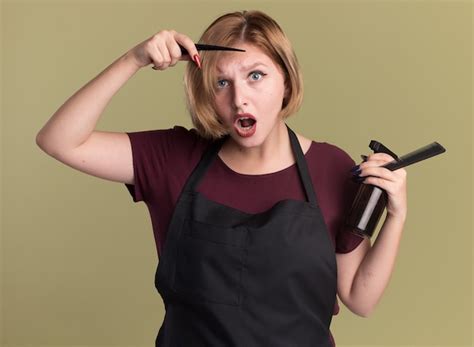 Peluquería de mujer hermosa joven en delantal sosteniendo pinza de pelo