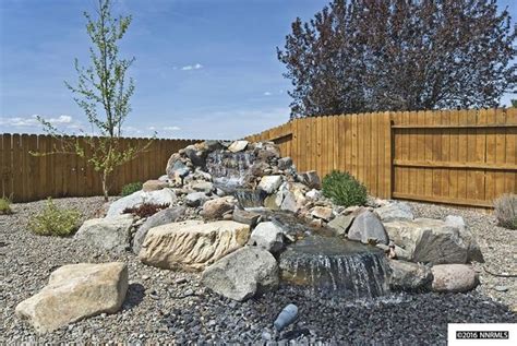 Rock Waterfall in Graveled Area with Trees and Fence