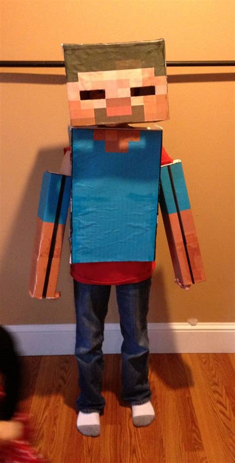 A Young Boy Is Dressed Up As A Minecraft Character In Front Of A Wall