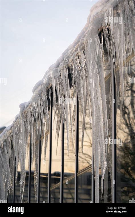 Icicles Hang From Roof And Wall In Winter Frozen Water From Melting