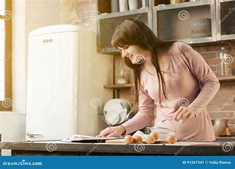 La Jeune Femme Fait Cuire Dans La Cuisine Avec Joie Elle Est Tenante Et Tenante Un Livre De