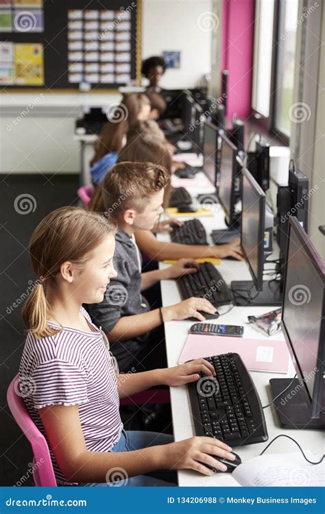 Line Of High School Students Working At Screens In Computer Class With