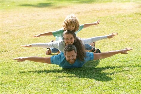 Familia tirada en la hierba en el parque padres dando niños piggybacks