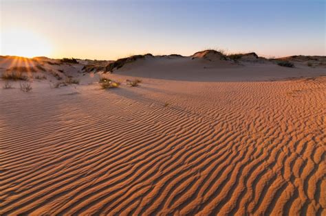 Puesta de sol sobre las dunas de arena en el desierto paisaje árido del