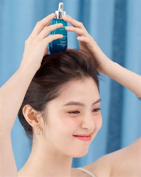 A Woman Holding Her Hair In Front Of Her Head With An Empty Bottle On