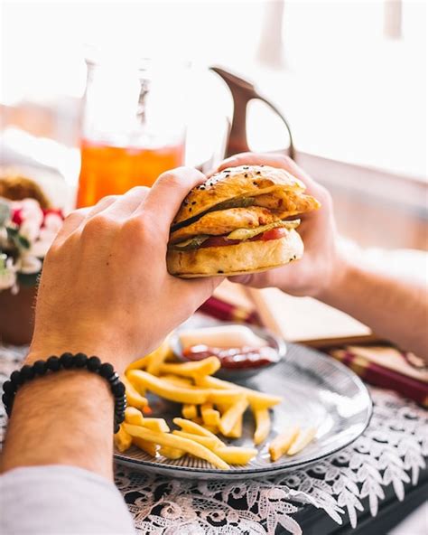 Homme Tenant Un Burger Au Poulet Servi Avec Des Frites Et De La Sauce