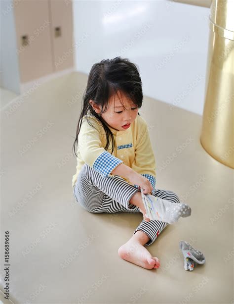 Adorable little girl trying to put a socks. Stock Photo | Adobe Stock